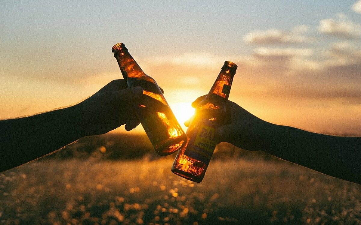 Zwei Leute stoßen mit Bier an Zwei Leute stoßen mit Bier an